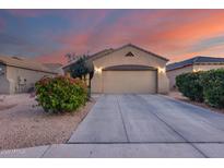 Charming single-story home featuring a well-maintained front yard and a two-car garage against a sunset sky at 15155 W Desert Hills Dr, Surprise, AZ 85379