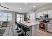 Bright kitchen featuring a large island with seating, stainless steel appliances, and sliding glass doors leading to the patio at 17988 W Deneen Way, Surprise, AZ 85374