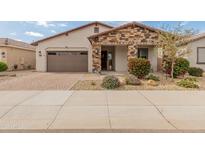 Charming single-story home featuring a stone facade, desert landscaping, and a brick-paved driveway at 24270 N 173Rd Ave, Surprise, AZ 85387