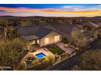 Aerial view of a backyard with a sparkling pool, fire pit, and beautifully landscaped seating area at sunset at 2550 W Pumpkin Ridge Dr, Anthem, AZ 85086