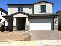 A charming two-story home with a white garage door, a welcoming porch, and stone accents at 43373 N Wollemi St, Queen Creek, AZ 85140