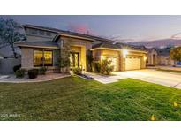 Charming home exterior with well-manicured lawn, warm lighting, and a three car garage at 69 E Benrich Dr, Gilbert, AZ 85295