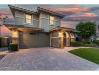Charming two-story home featuring a stone-accented entrance, wide driveway, and a well-maintained lawn at twilight at 11544 W Ashby Dr, Peoria, AZ 85383