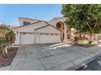 Elegant stucco home featuring a three-car garage and a beautiful arched entryway with a balcony at 1449 W Commerce Ave, Gilbert, AZ 85233
