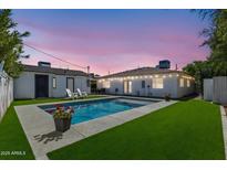 Backyard oasis with a refreshing pool, artificial grass, and outdoor seating perfect for entertaining at 3516 E Earll Dr, Phoenix, AZ 85018