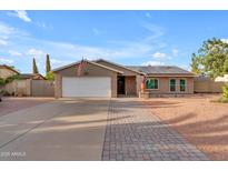 Charming single-story home featuring a brick facade, two-car garage, and manicured landscaping at 6126 W Sweetwater Ave, Glendale, AZ 85304
