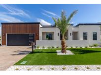 Beautiful modern home featuring a well-manicured lawn, stylish landscaping, and a sleek black garage door at 7325 E Virginia Ave, Scottsdale, AZ 85257