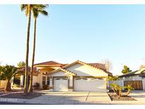 Charming single-story home featuring a three-car garage, tile roof, and lush palm trees at 1490 W Laurel Ave, Gilbert, AZ 85233