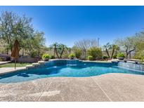 A pristine pool featuring a tranquil waterfall, surrounded by lush landscaping and clear blue skies at 26722 N 90Th Ln, Peoria, AZ 85383