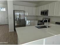 Modern kitchen features stainless steel appliances, white cabinetry, and a central island with a sink at 4330 N 94Th Ave, Phoenix, AZ 85037