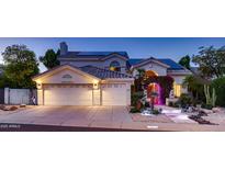 Charming home featuring a three-car garage, solar panels, and inviting entrance with lush landscaping at twilight at 1614 E Kathleen Rd, Phoenix, AZ 85022
