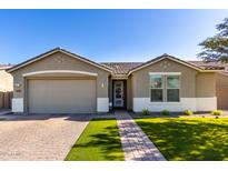 Charming single-story home featuring a well-manicured lawn, a brick driveway, and a two-car garage at 18735 W San Juan Ave, Litchfield Park, AZ 85340