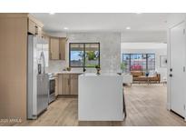 Open kitchen with an island, stainless steel appliances, modern cabinets, and tile backsplash at 3517 E Hartford Ave, Phoenix, AZ 85032