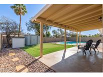 Covered patio with view of putting green, shed, lush landscape, and a private pool, creating an outdoor oasis at 1537 W Impala Ave, Mesa, AZ 85202