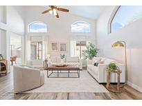 Bright living room featuring soaring ceilings, many windows, neutral decor, and wood-look flooring at 1728 E Barbarita Ave, Gilbert, AZ 85234