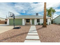 Charming single-story home with desert landscaping, walkway, a basketball hoop, and a green garage door at 1347 S Almond Cir, Mesa, AZ 85204