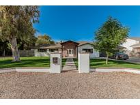 Charming single-story home featuring a well-manicured lawn, white facade, and brick entryway at 2218 E Maplewood St, Gilbert, AZ 85297