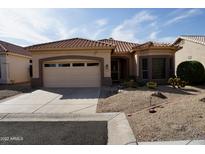 Charming single-story home with a well-manicured yard and a two-car garage on a sunny day at 11564 W Mule Deer Ct, Surprise, AZ 85378