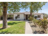 Charming single-story home with lush green lawn, mature trees, and a welcoming walkway at 2163 W Flower St, Phoenix, AZ 85015