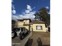 Two-story home with a tan exterior, well-manicured lawn, and a Jeep parked in the driveway at 2521 N 89Th Ave, Phoenix, AZ 85037