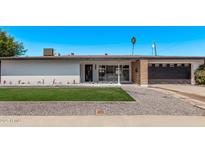 Charming single-story home with well-manicured lawn, rock landscaping, and an attached two car garage at 1922 W Joan De Arc Ave, Phoenix, AZ 85029