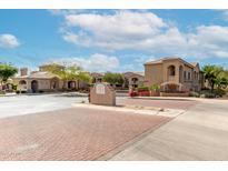 Welcoming community entrance with brick-paved road and desert landscaping under a partly cloudy sky at 29606 N Tatum Blvd # 121, Cave Creek, AZ 85331