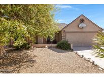 Charming single-story home showcasing a tidy gravel yard, tree and an attached two-car garage at 6909 W Cherry Hills Dr, Peoria, AZ 85345