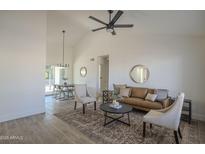 Bright living room featuring tile floors, ceiling fan, leather couch, and access to dining area at 801 E Piute Ave, Phoenix, AZ 85024