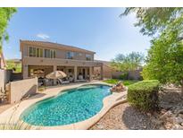 An inviting backyard pool features a waterfall, covered patio, lush landscaping, and desert-style rock at 10558 E Meadowhill Dr, Scottsdale, AZ 85255