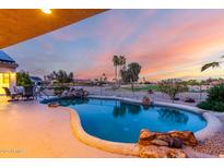 Beautiful backyard pool featuring rock waterfall and comfortable seating area perfect for entertaining guests at 19793 N Tapestry Ct, Surprise, AZ 85374