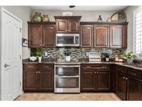 Modern kitchen boasts granite countertops, dark wood cabinets, stainless steel appliances, and mosaic backsplash at 2512 E Vermont Dr, Gilbert, AZ 85295