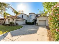 Elegant stucco home with a circular driveway, lush landscaping, and a three-car garage at 4497 E Carriage Way, Gilbert, AZ 85297