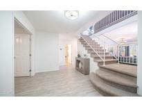 Bright foyer featuring a staircase with carpeted steps and white railing, plus wood-look tile flooring at 7516 E Christmas Cholla Dr, Scottsdale, AZ 85255