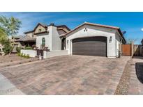 Beautiful home exterior with a brown garage door and a cobblestone driveway on a sunny day at 9742 W Los Gatos Dr, Peoria, AZ 85383