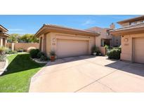 Spacious two-car garage and driveway with a well-manicured lawn and desert landscaping at 15240 N Clubgate Dr # 162, Scottsdale, AZ 85254