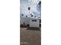 View of the white storage shed and gravel ground surrounding a house with palm trees in the background at 25 S 102Nd St # 91, Mesa, AZ 85208