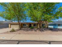 Charming single-story home featuring a gravel yard, a two-car garage, and mature shade trees at 3932 E Shaw Butte Dr, Phoenix, AZ 85028