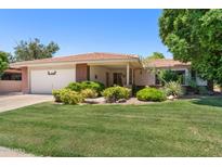 Charming single-story home with manicured lawn, lush landscaping, and a welcoming front entrance at 1202 Leisure World --, Mesa, AZ 85206