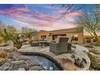 Desert home backyard with a cozy seating area near a rock waterfall feature and view of the beautiful Arizona sunset at 37170 N Greythorn Cir, Carefree, AZ 85377