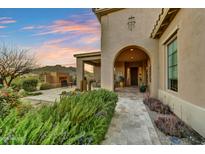 Charming home exterior showcasing a covered porch, desert landscaping, and mountain views in the background at 37170 N Greythorn Cir, Carefree, AZ 85377