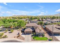 Expansive aerial view of a home with a tiled roof, a pool, and mountain views in the distance, showing the neighborhood at 4455 E Palmdale Ln, Gilbert, AZ 85298