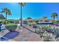 Single-story home featuring desert landscaping with mature trees, cacti, and decorative rock at 5811 E Edgemont Ave, Scottsdale, AZ 85257