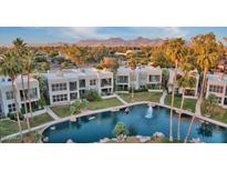 Stunning aerial view of a community with a beautiful pool and lush landscaping with views of the mountains in the distance at 7700 E Gainey Ranch Rd # 222, Scottsdale, AZ 85258