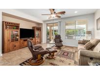 Inviting living room with neutral tones, tile floors, ceiling fan, and sliding doors to backyard at 26237 W Vista North Dr, Buckeye, AZ 85396
