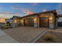 Charming home featuring a three car garage and brick paver driveway at dusk at 5812 E Sanford St, Mesa, AZ 85215