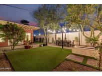 Expansive backyard featuring a patio, dining area, manicured lawn, and fire pit, perfect for relaxation and entertaining at 1513 W Mitchell Dr, Phoenix, AZ 85015