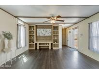 Spacious living room featuring modern flooring, a ceiling fan, and a built-in entertainment center at 255 S 92Nd Pl, Mesa, AZ 85208