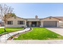 Charming home featuring a lush front lawn, stone accents, shutters, and a welcoming two-car garage at 5333 E Catalina Ave, Mesa, AZ 85206