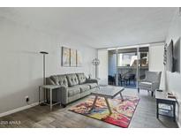 Bright living room featuring a gray sofa, colorful rug, and sliding glass doors to a patio at 7625 E Camelback Rd # A114, Scottsdale, AZ 85251