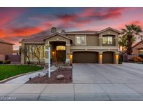 Beautiful two-story home with a well-manicured lawn, three-car garage and mature palm trees at sunset at 4812 S Windstream Pl, Chandler, AZ 85249